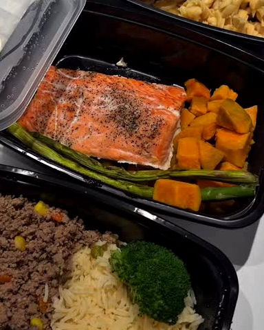 Hilera de bandejas selladas con salmón, boniato, carne molida y arroz blanco