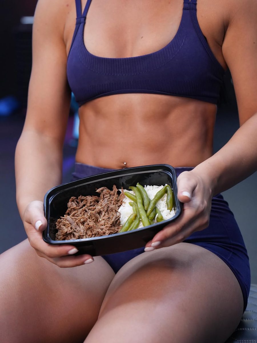 Una clienta sostiene una bandeja de carne deshebrada con arroz y habichuelas después de entrenar
